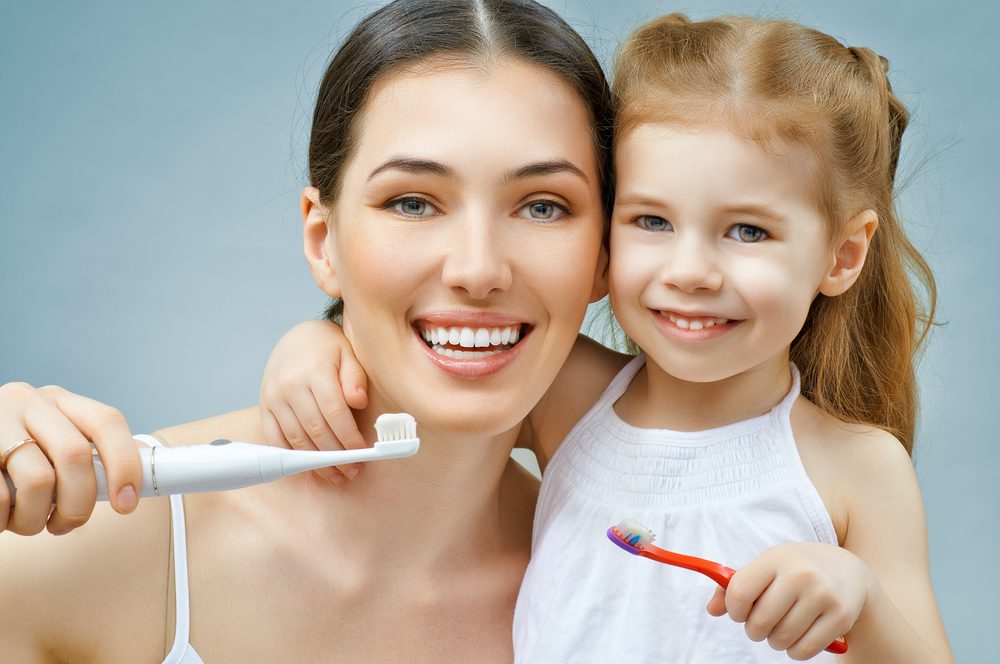 Mother and daughter holding toothbrush